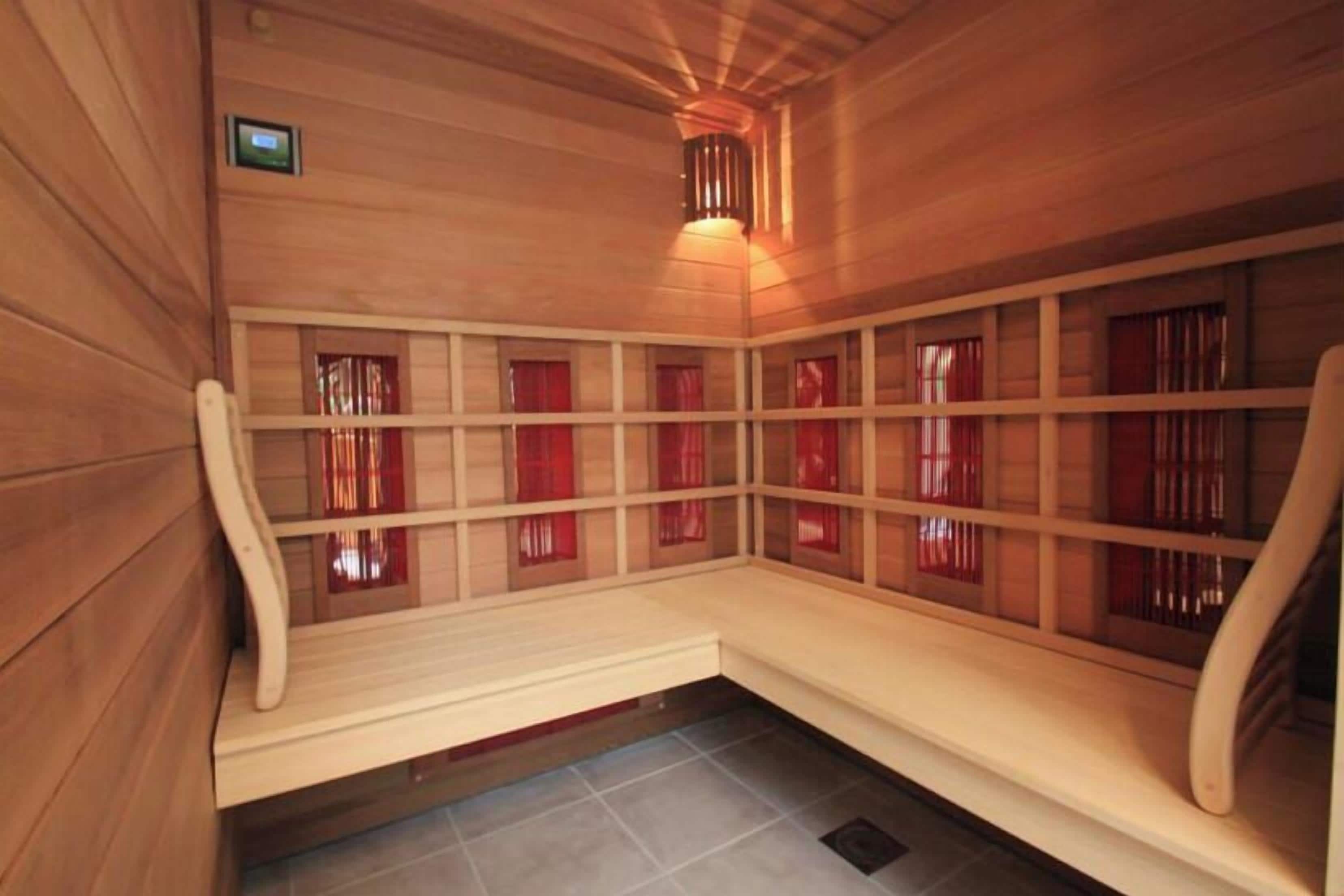 Un sauna avec des murs, des bancs et des rideaux rouges, le tout en bois.