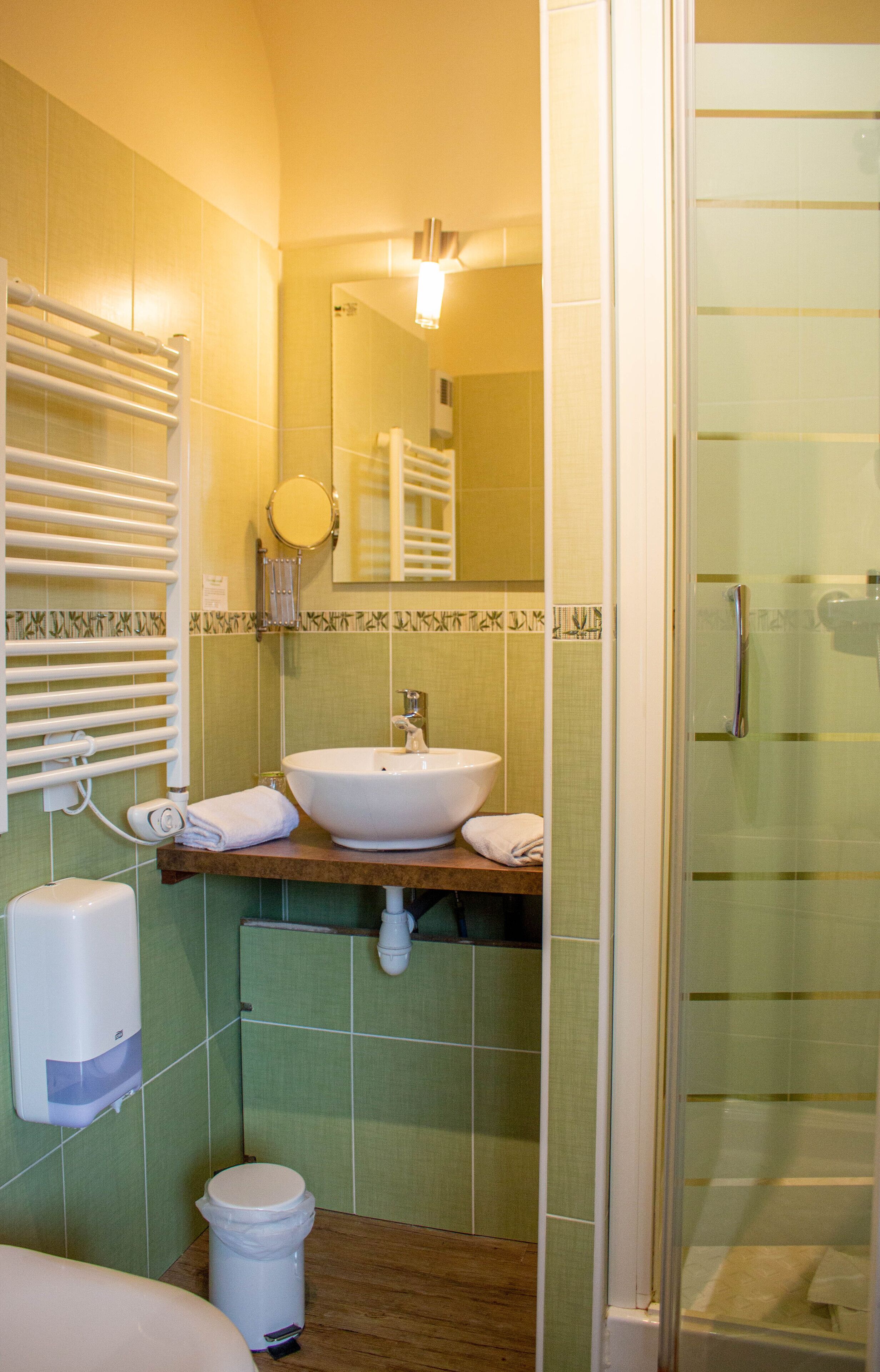 Un baño con lavabo, espejo, toallero y cabina de ducha de vidrio.