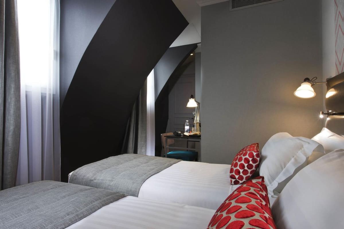Ein Hotelzimmer mit zwei Betten, einem Schreibtisch und einem Stuhl.