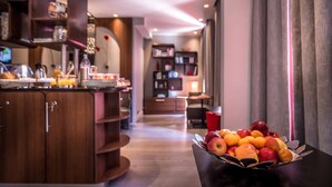 Een moderne hotelkamer met een houten kast, een schaal fruit op de tafel en uitzicht op de eetruimte.