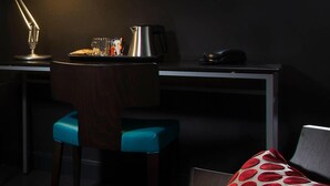 Een kleine kamer met een bureau, stoel en een bed met een kussen met stipjes.