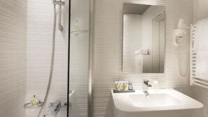 Een moderne badkamer met een glazen douchecabine, een witte wastafel en een spiegel.