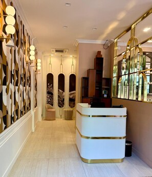 A hotel lobby with a reception desk, a patterned wall, and a mirror reflecting the interior. - Hôtel Garance (Paris)