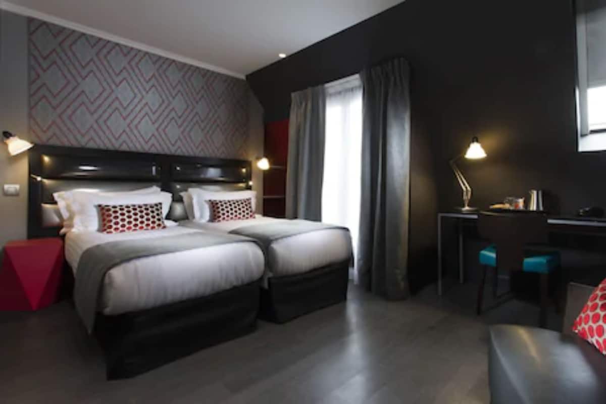 Ein modernes Hotelzimmer mit zwei Betten, einem Schreibtisch und einer Sitzecke.