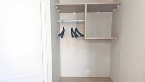 Een inloopkast met houten planken en een klein krukje.