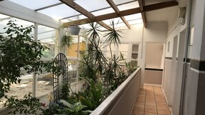 A conservatory with a variety of plants, a tiled floor, and a view of the outside. - Hôtel Paradis (Bormes-Les-Mimosas)