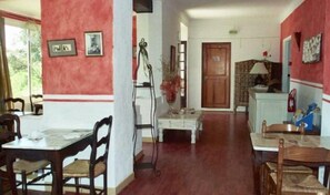 A dining area with a table and chairs, a staircase, and a door leading to another room. - Hôtel Paradis (Bormes-Les-Mimosas)