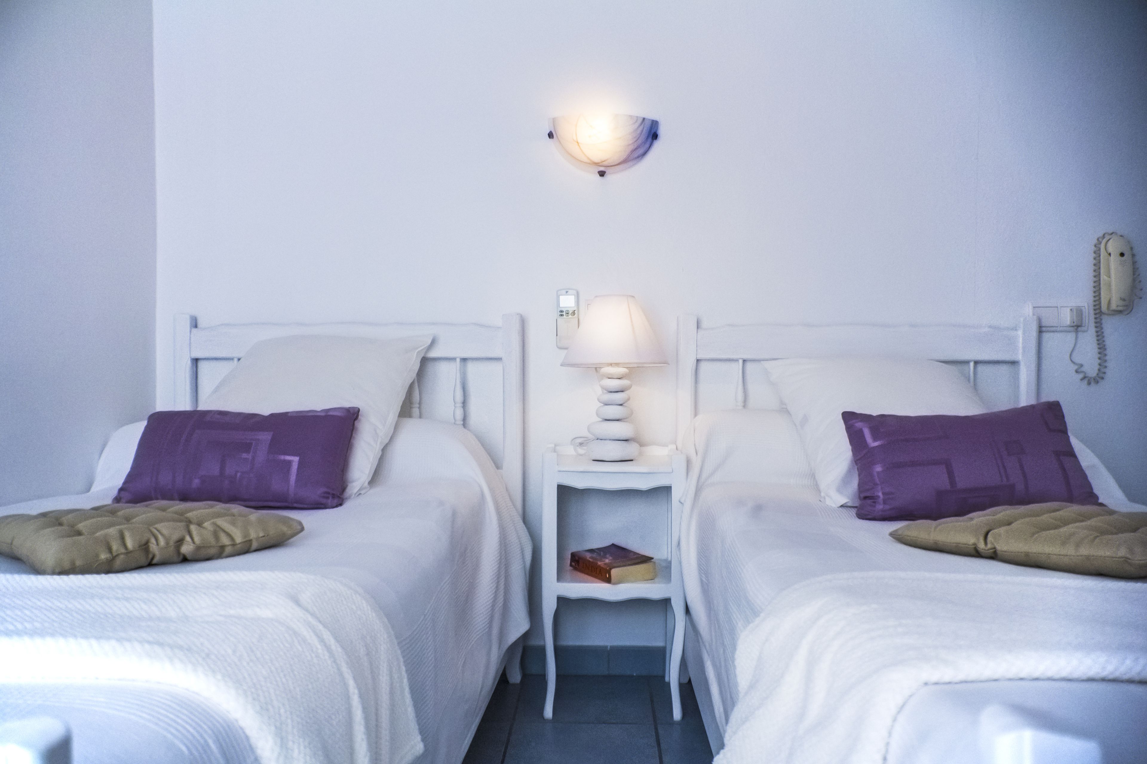 Habitación doble con dos camas, una mesita de noche con lámpara, teléfono y un libro.