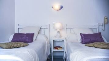 Habitación doble con dos camas, una mesita de noche con lámpara, teléfono y un libro.