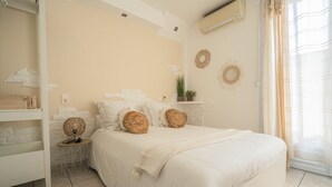 Une chambre à coucher comprenant un lit, une table de chevet, une étagère avec des objets décoratifs et une fenêtre avec des rideaux.