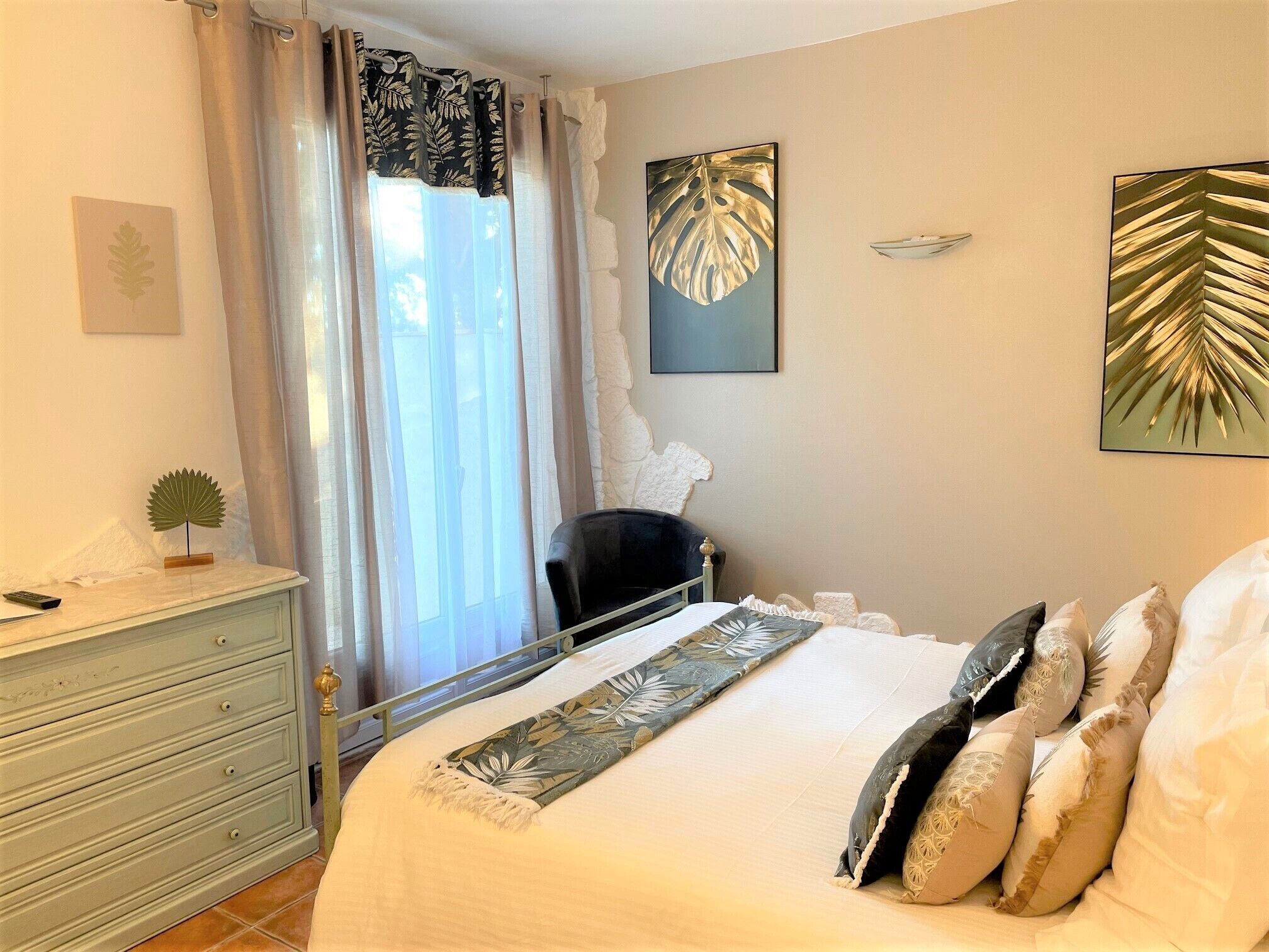 Ein Schlafzimmer mit Bett, Schminktisch, Stuhl und Bildern an den Wänden.