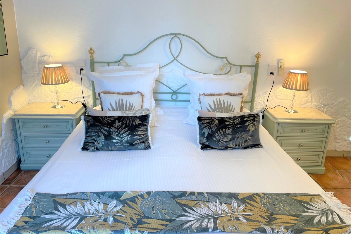 A bedroom with a bed, two nightstands, two lamps, and a patterned bedspread.