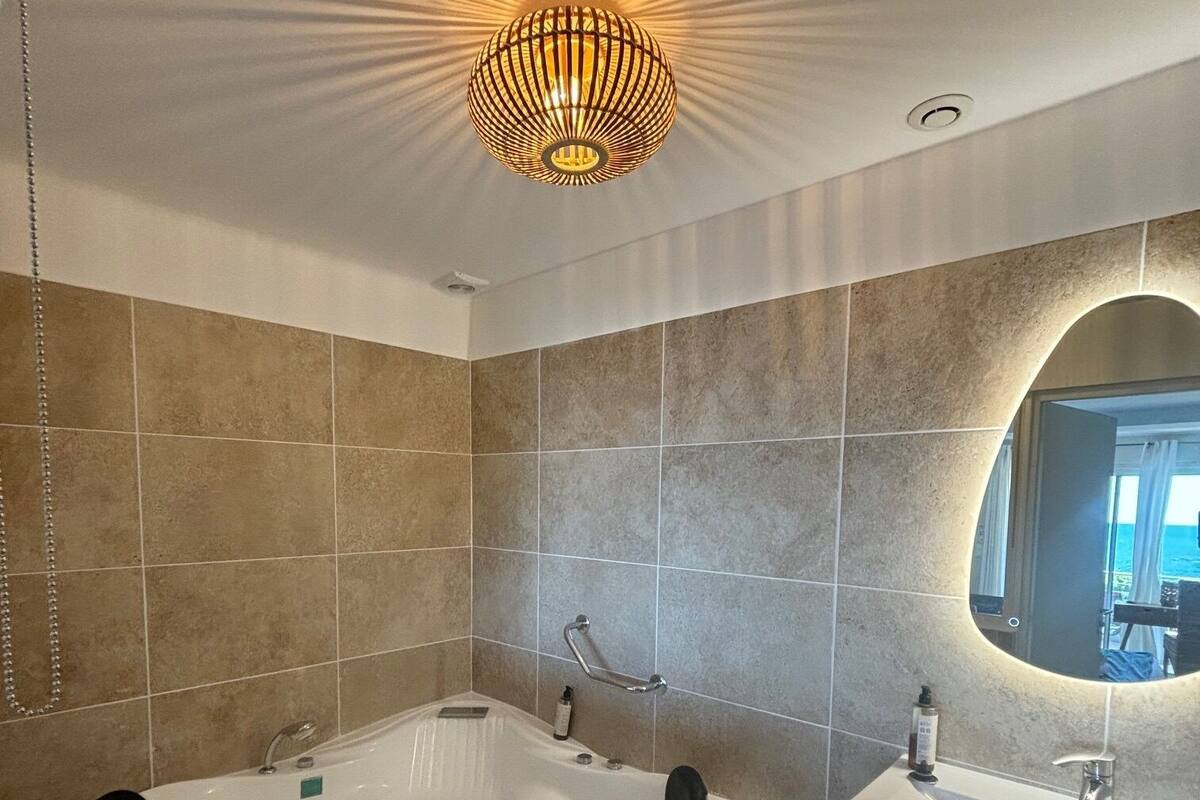 Une salle de bain moderne avec une baignoire sur pieds, un meuble-lavabo avec un miroir et un luminaire au plafond.