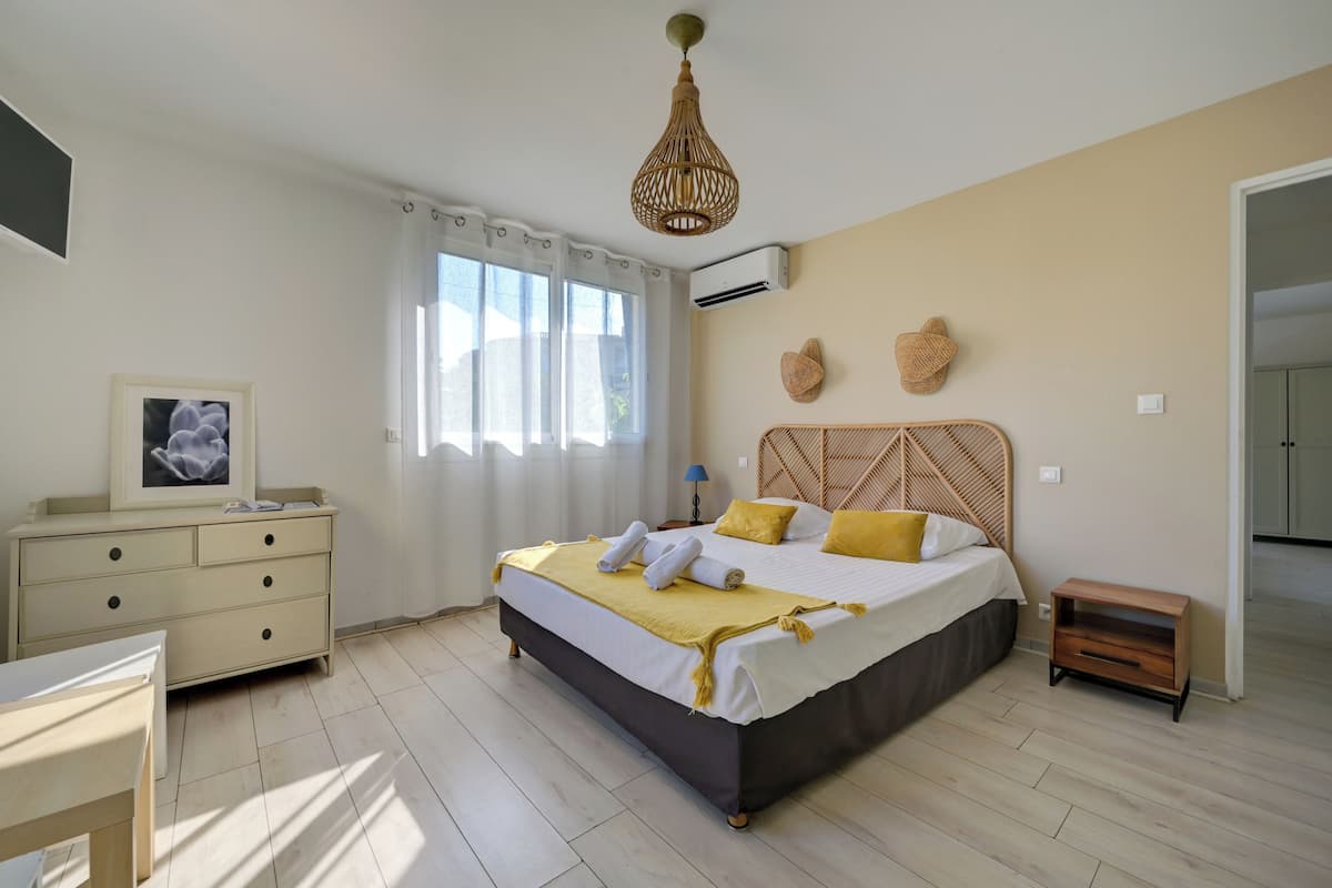 Une chambre à coucher avec un lit, une table de chevet, une commode et un cadre photo accroché au mur.