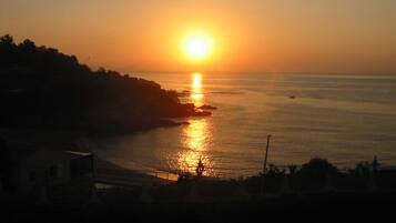 A sunset over a coastal area with a view of the sea and a rocky shoreline.