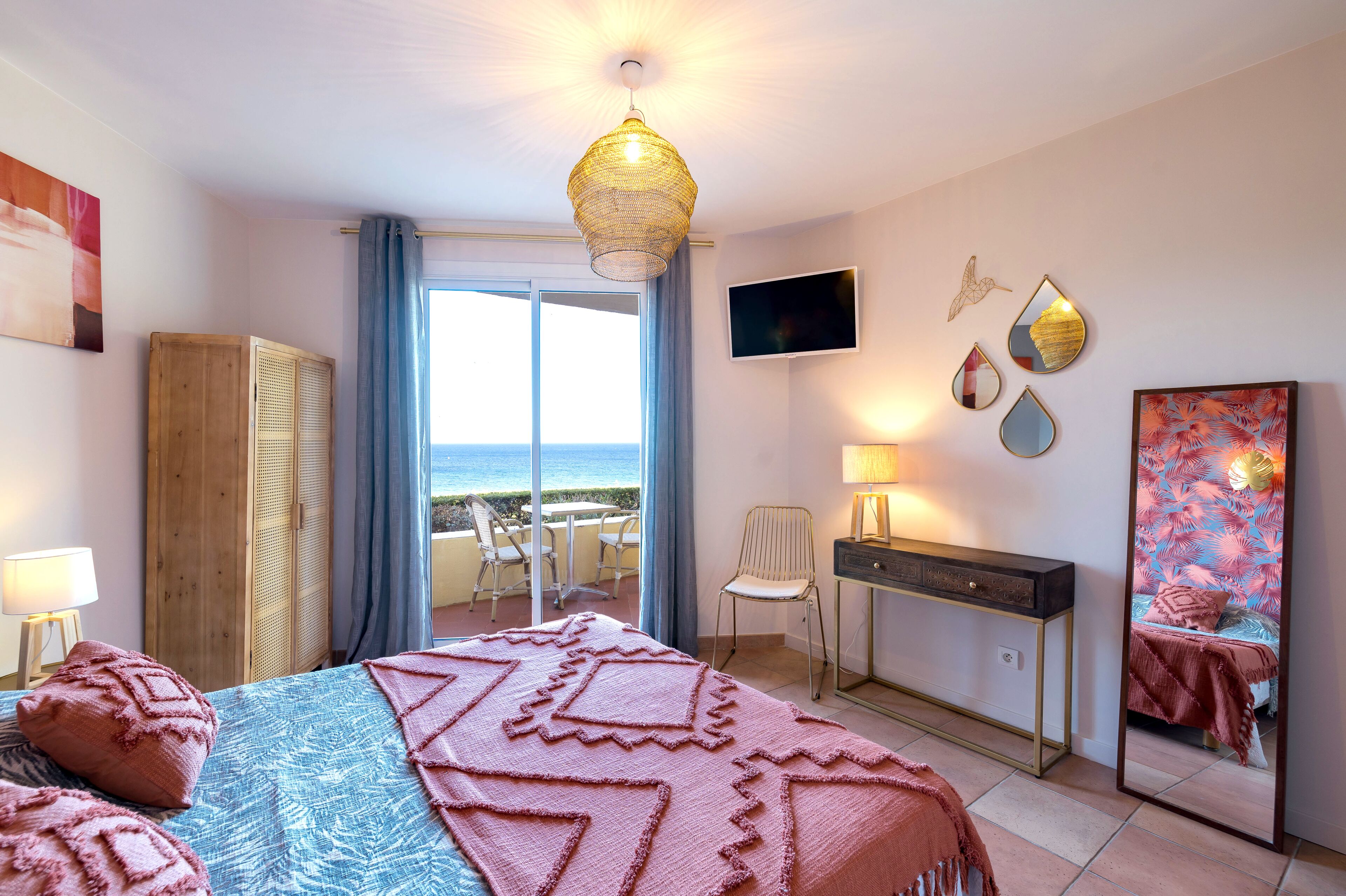 Ein Schlafzimmer mit Bett, Schreibtisch, Stuhl, Fernseher und einem Balkon mit Aussicht.