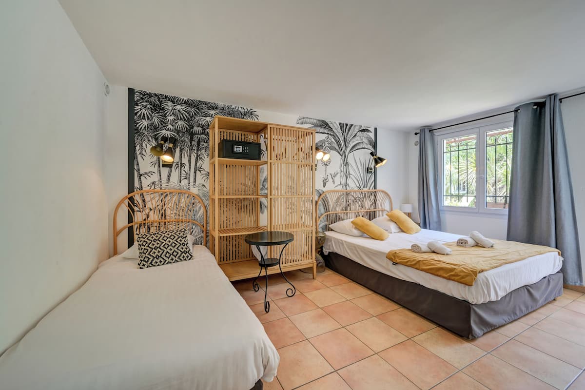 Une chambre avec deux lits, une armoire en bois, une petite table et une fresque murale.