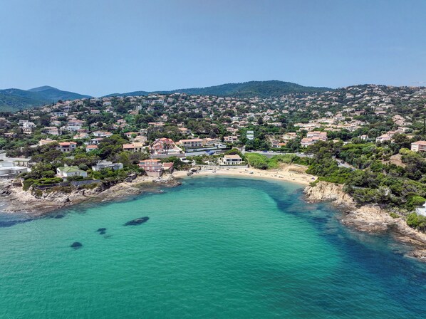 A coastal town with a beach, houses, and a mountainous backdrop.