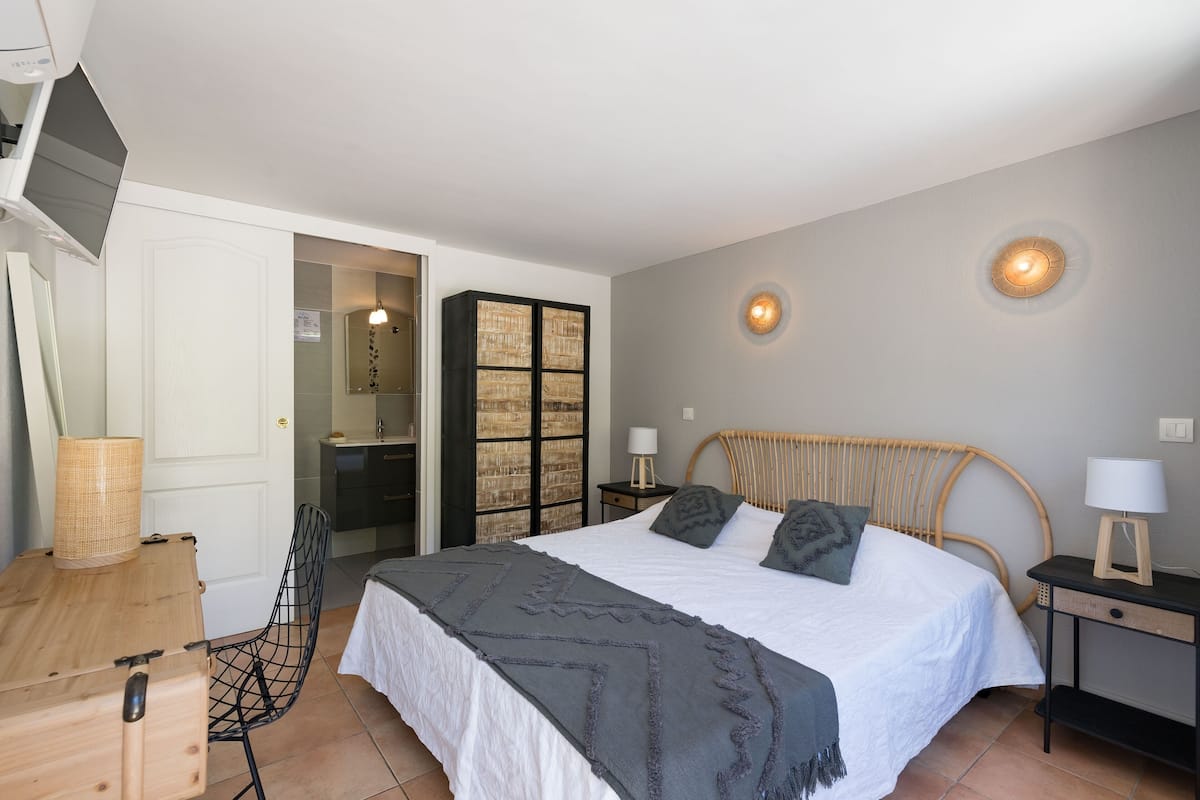 Une chambre à coucher comprenant un lit, des tables de chevet, une chaise, un bureau et un téléviseur.