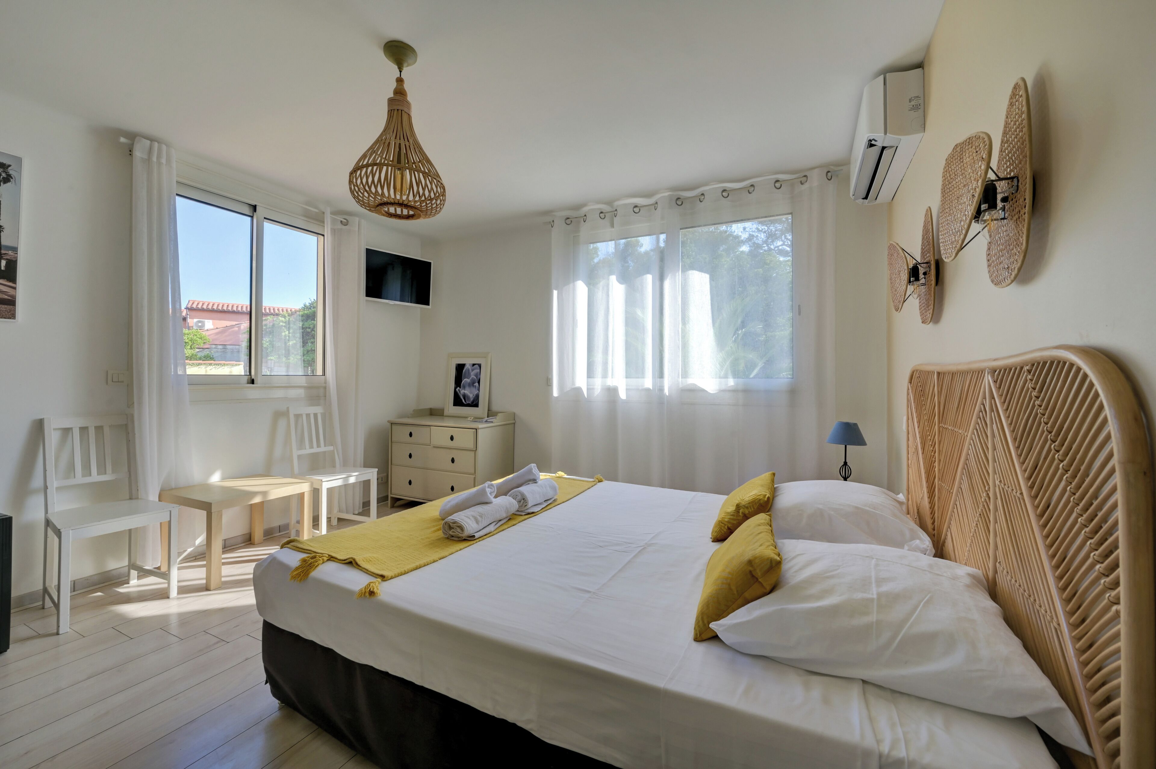 Une chambre d’hôtel avec un lit, un bureau, des chaises, une télévision et une fenêtre avec des rideaux.