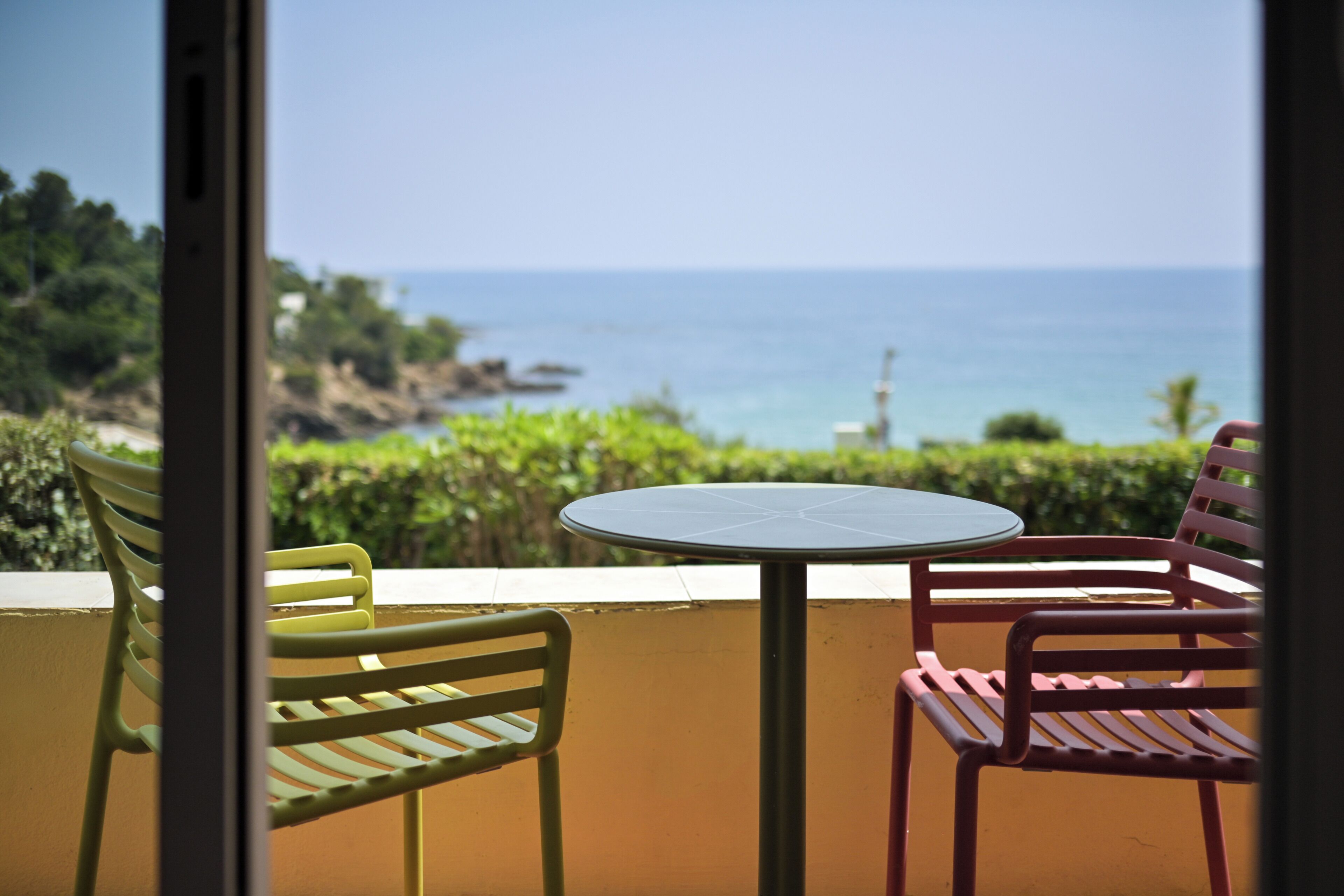 Un balcon avec une table et des chaises, donnant sur un paysage côtier.