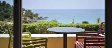Un balcon avec une table et des chaises, donnant sur un paysage côtier.