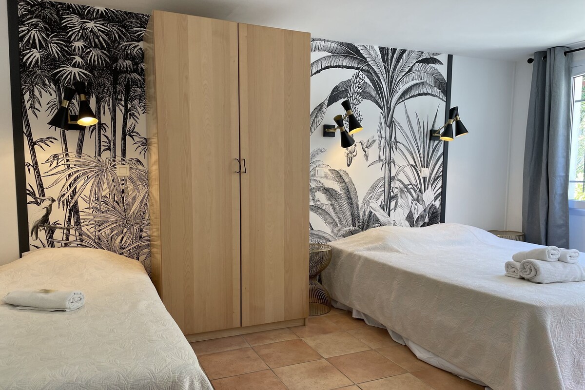 A hotel room with two beds, a wardrobe, and a large wall mural.