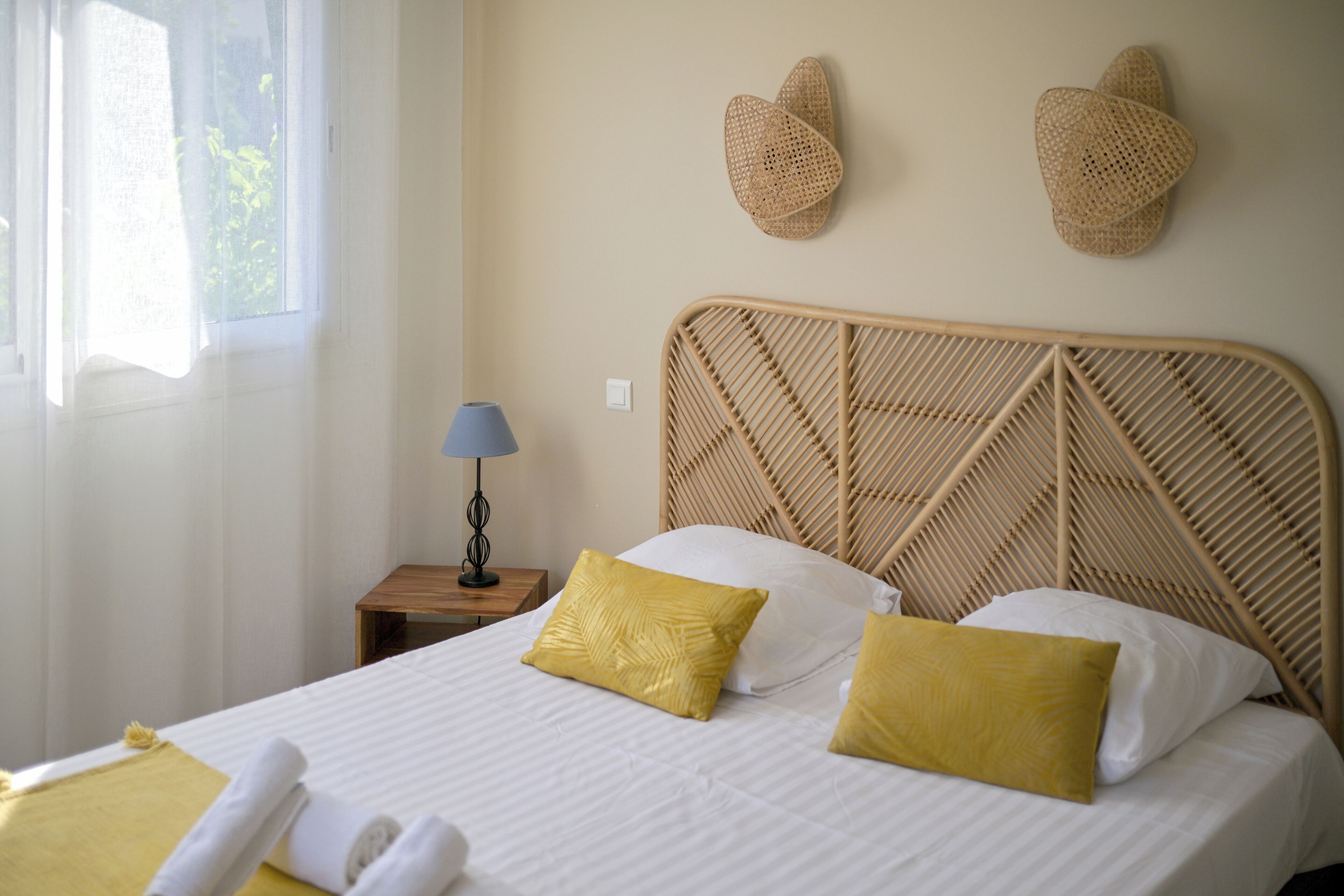 A neatly made bed with two pillows, a bedside lamp, and two wall-mounted hats.