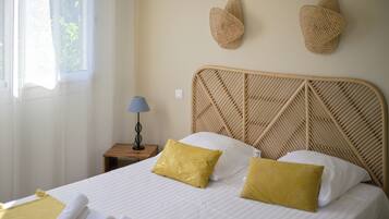 A neatly made bed with two pillows, a bedside lamp, and two wall-mounted hats.