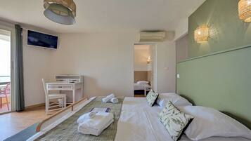 Een hotelkamer met een bed, een bureau, een stoel, een televisie en een balkon.