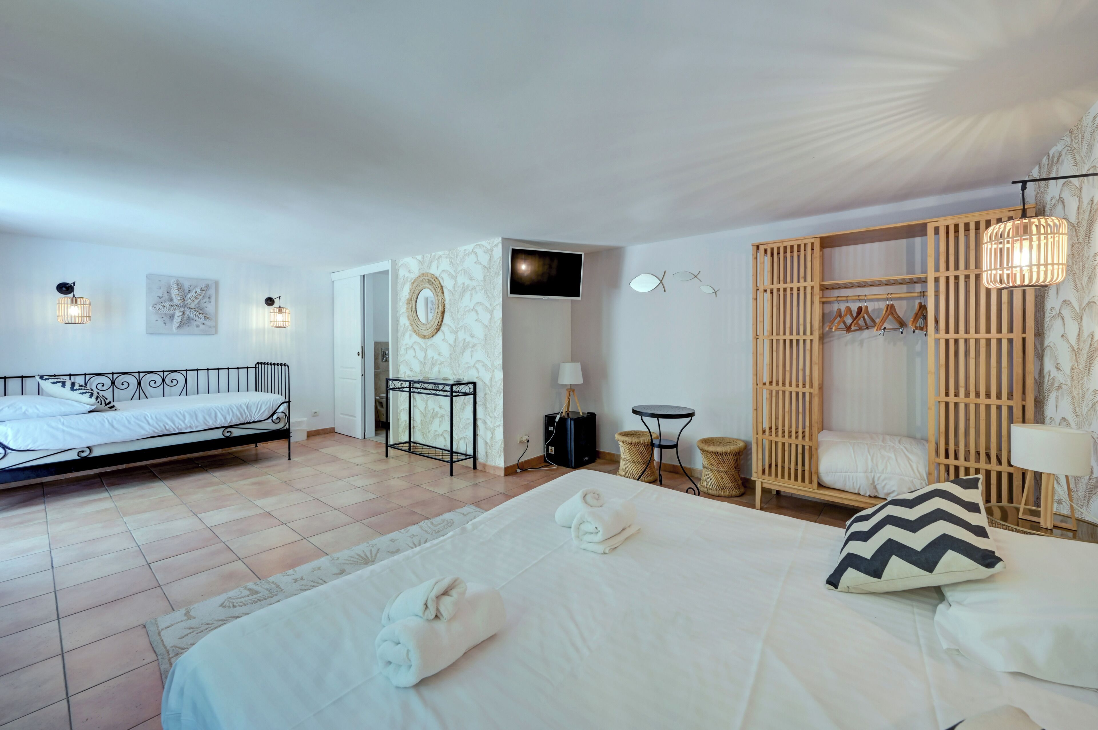 A hotel room with a bed, a desk, a TV, a wardrobe, and a seating area.