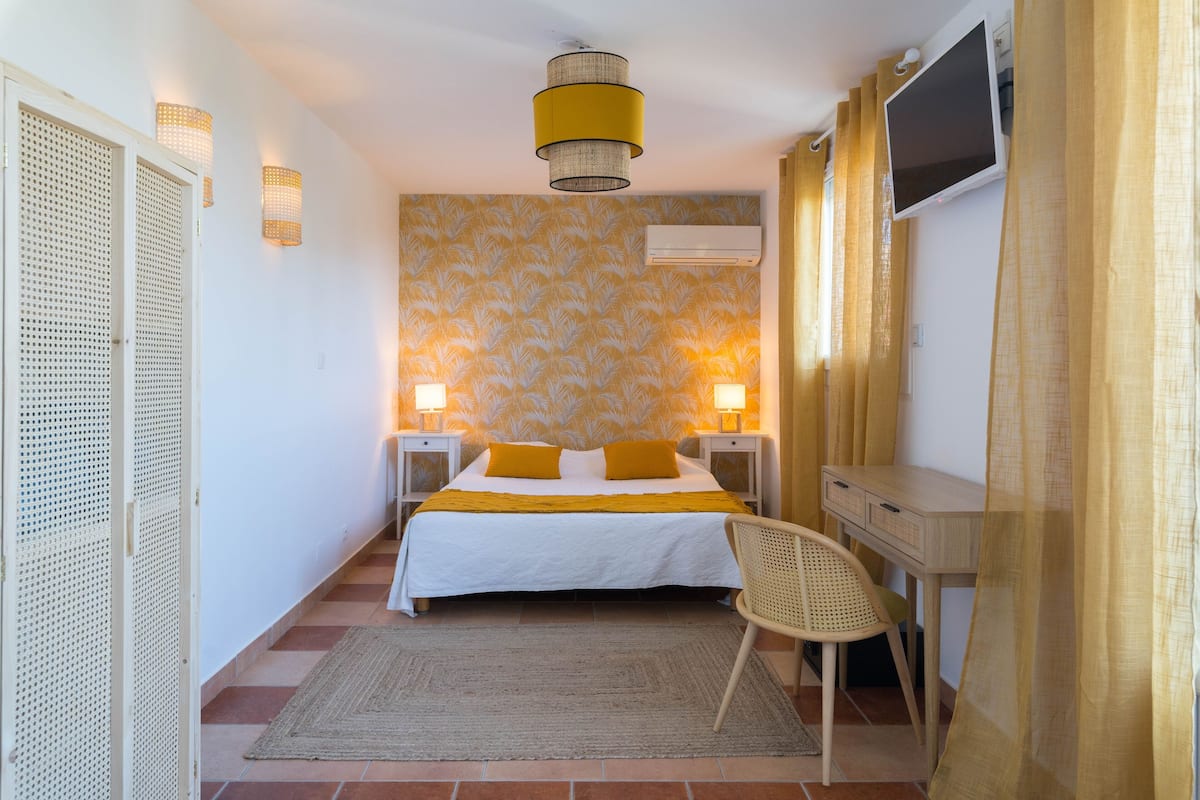Une chambre à coucher avec un lit, des lampes de chevet, un bureau et un téléviseur.