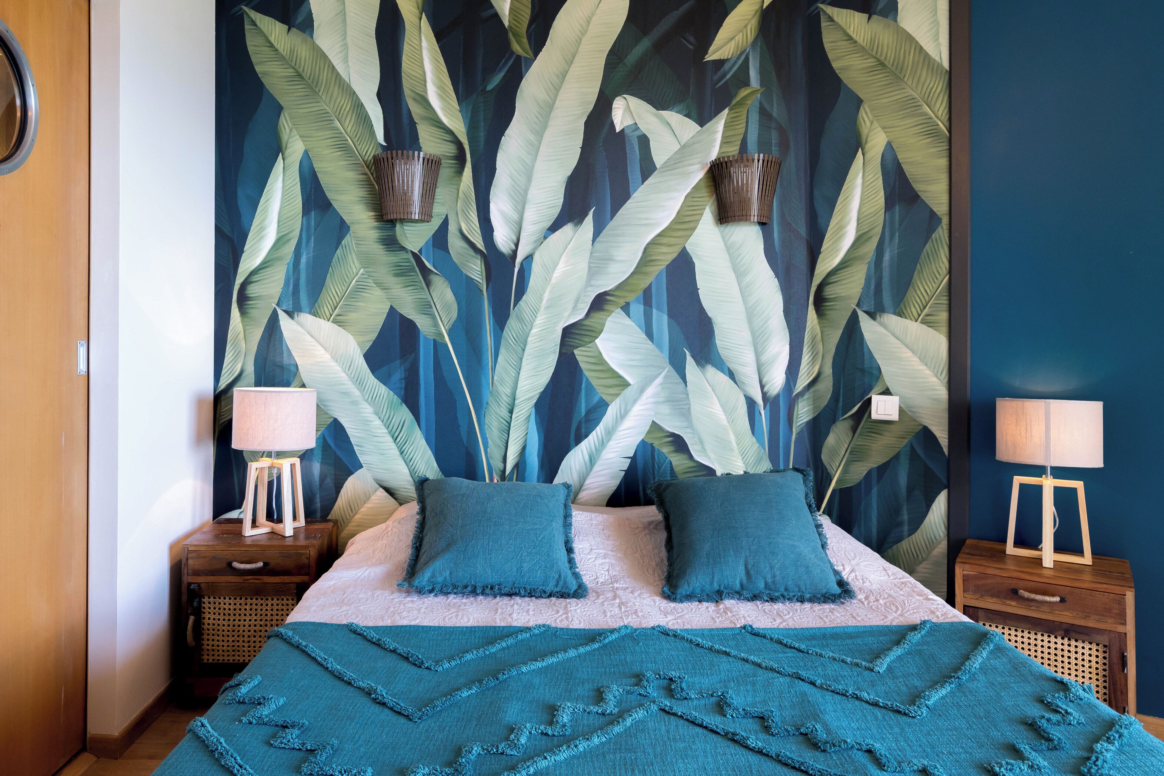 Un dormitorio con una cama grande, dos mesitas de noche, un mural en la pared y una puerta de madera.