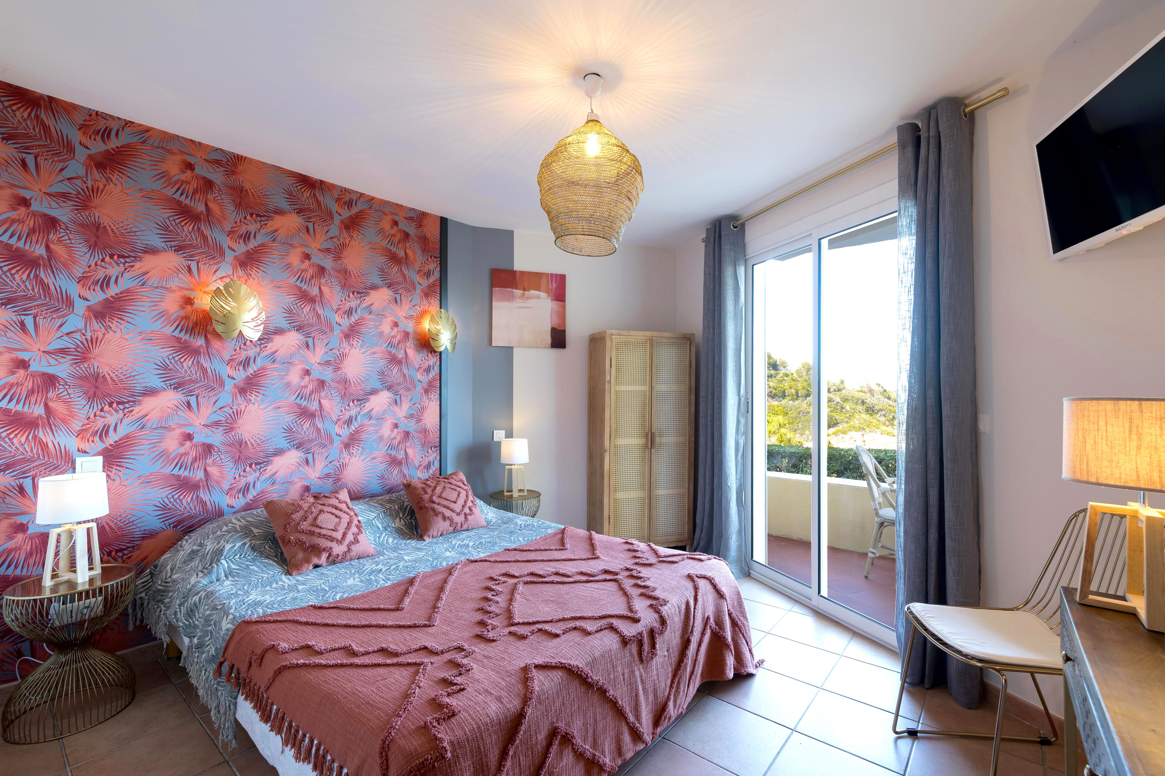 Une chambre à coucher comprenant un lit, une table de chevet, une lampe, une armoire et un téléviseur.