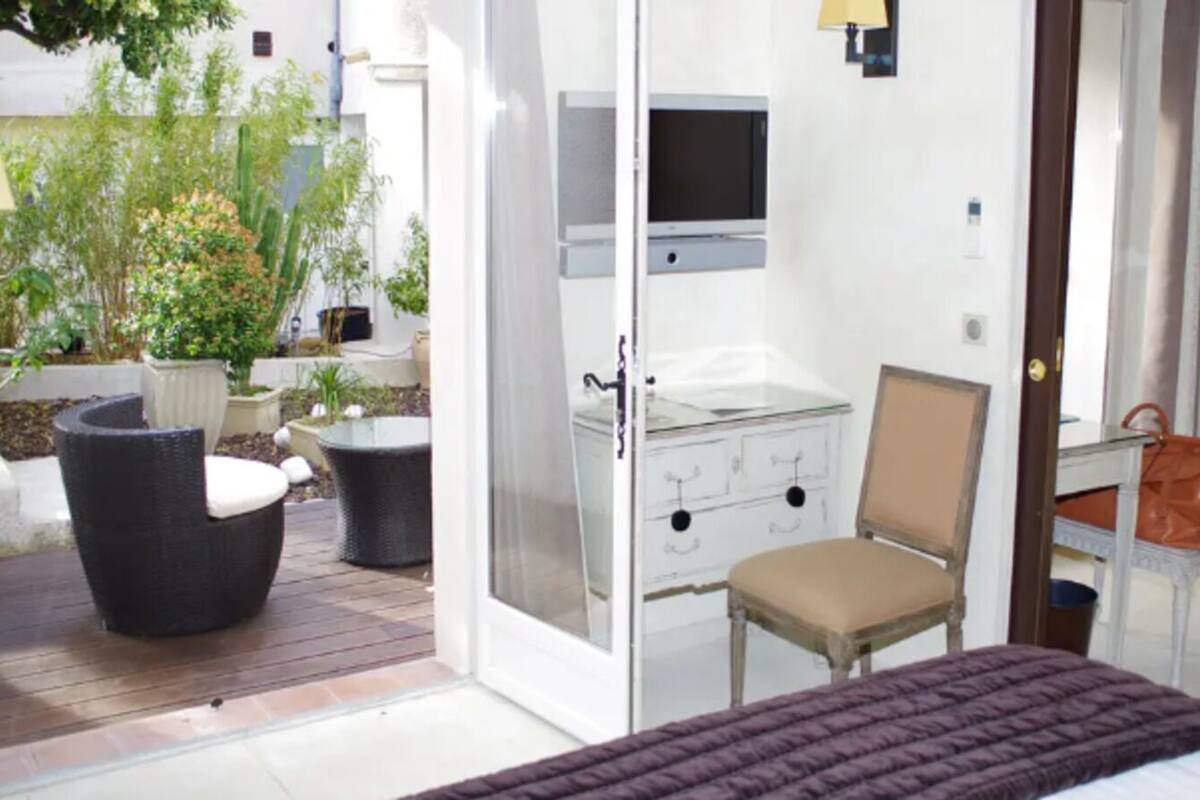 Une chambre avec un lit, une chaise, un bureau, une télévision et une vue sur le jardin.