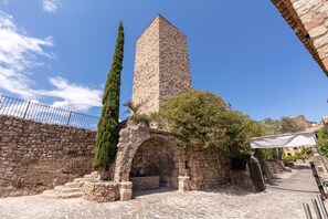 A stone tower with an arched entrance, a stone wall, and a paved pathway. - Le Chateau d'Argens (Les Arcs-sur-Argens)