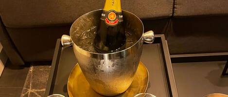 Een fles Taittinger Brut champagne in een metalen emmer op een dienblad, met twee glazen en een kaars.