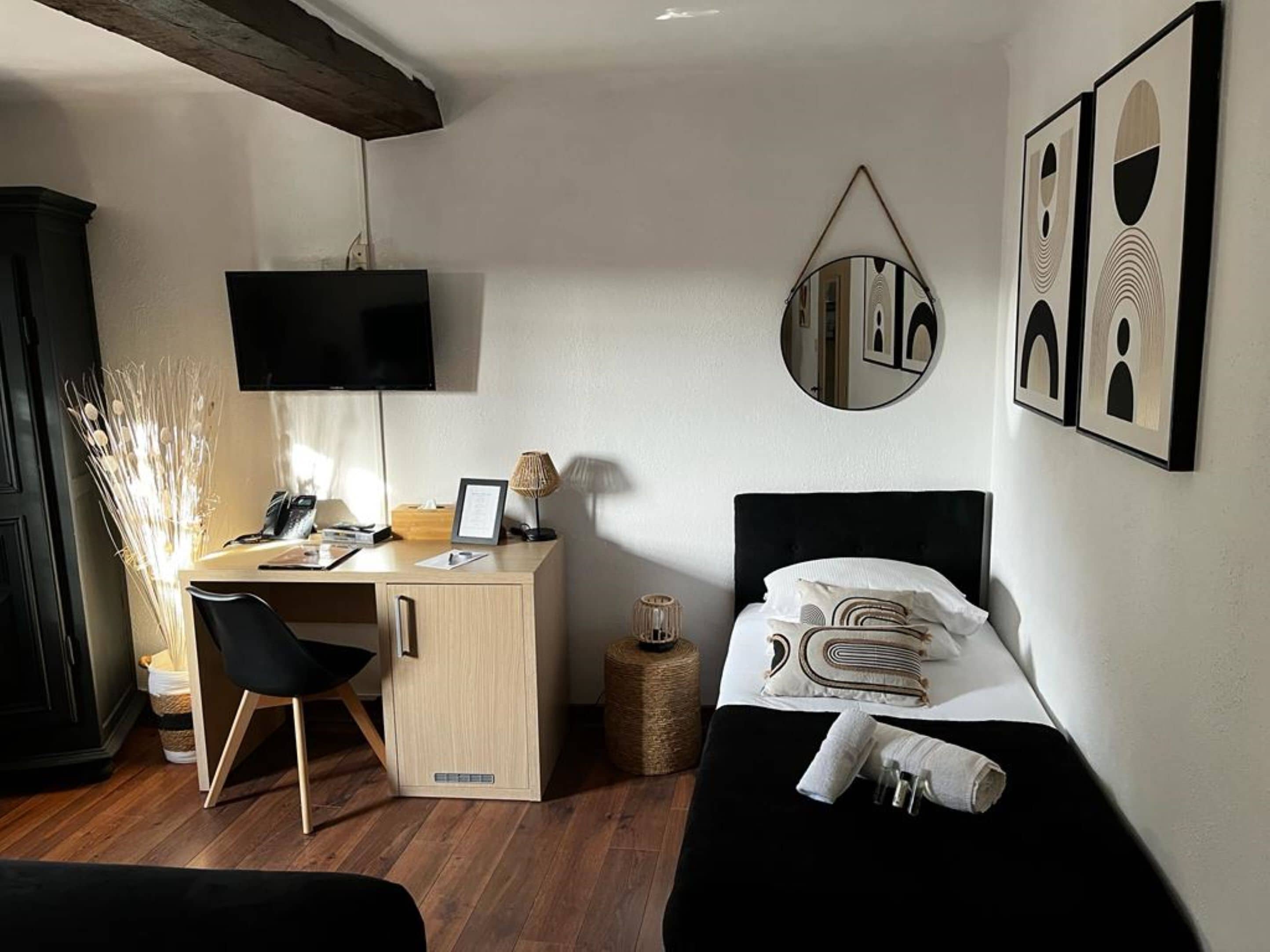 Habitació d'hotel amb llit, escriptori amb cadira, televisió i obres d'art a les parets.