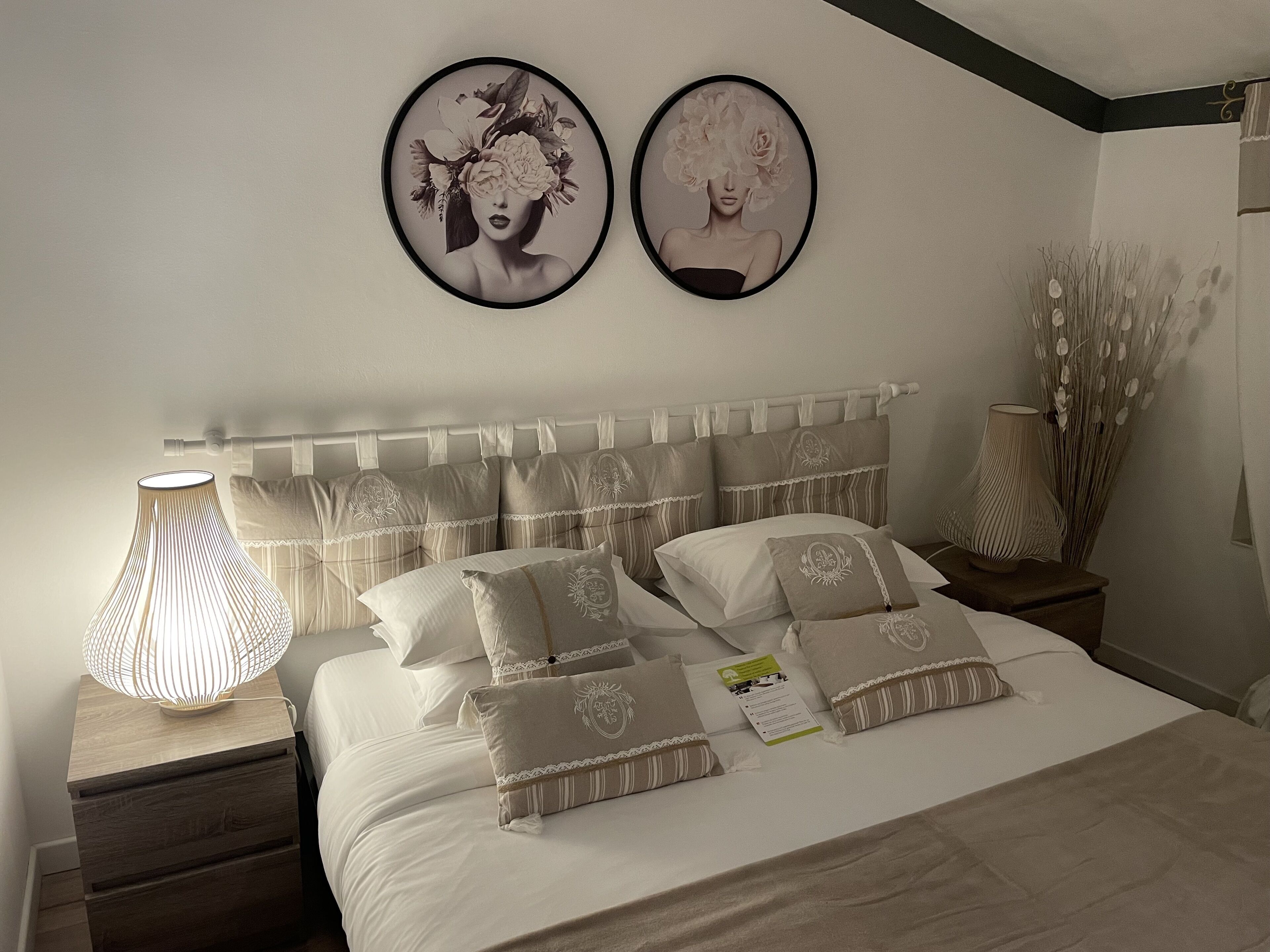 A neatly made bed with a striped headboard, a bedside lamp, and two framed artworks on the wall.