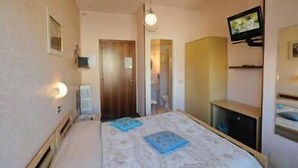 A bedroom with a bed, a television mounted on the wall, a mirror, and a door leading to another room. - Hotel Elena (Stresa)