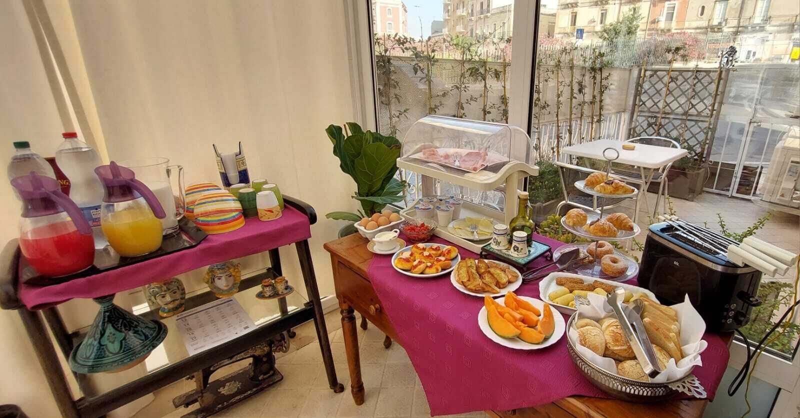 A breakfast buffet with various food items and a toaster on a table near a window.