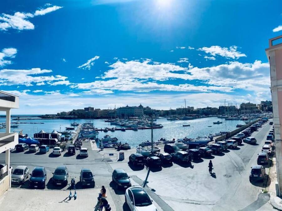 Un puerto deportivo con barcos, un estacionamiento y edificios con balcones.