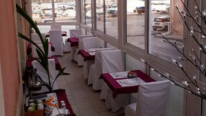 Ein Restaurant mit überdachter Außenterrasse, weißen Tischdecken und Blick auf Boote und Gebäude.