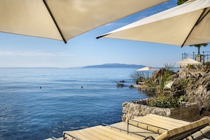 A seaside terrace with lounge chairs and umbrellas overlooking the sea. - Hotel Kvarner - Liburnia (Opatija)