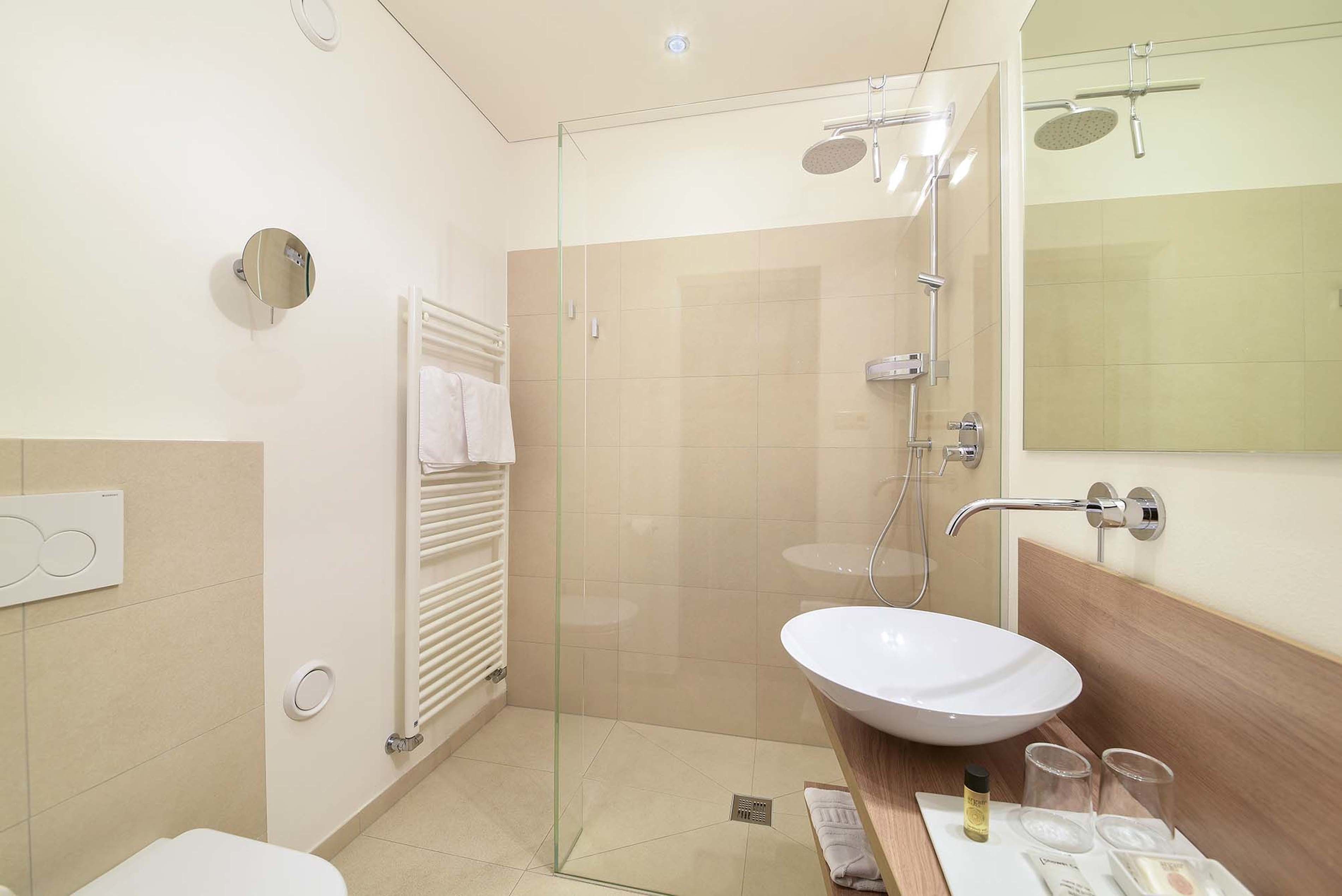 A modern bathroom with a glass-enclosed shower, a white sink, and a towel rack.