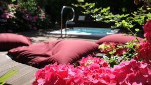A pool area with red cushions and pink flowers. - Gartenresidence Zea Curtis (Merano)
