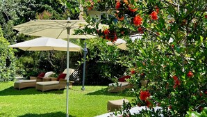 A garden with outdoor seating, a building in the background, and a clear blue sky. - Gartenresidence Zea Curtis (Merano)