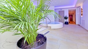 A modern interior with a large potted plant, a circular seating area, and a visible door leading to another room. - Gartenresidence Zea Curtis (Merano)