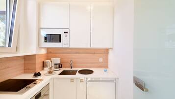 A compact kitchen with a microwave, coffee maker, sink, and a built-in oven.