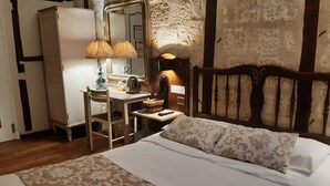Un dormitorio con una cama, un escritorio con lámpara, un espejo y cabecera de madera.
